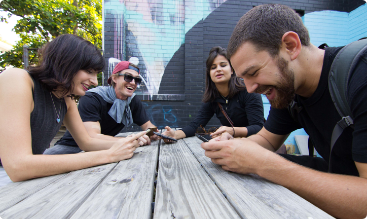 Teammates huddled around a phone solving a scavenger hunt riddle